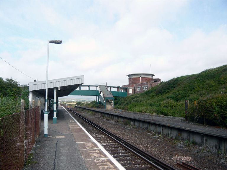Bishopstone station from the platform side. This is the other side of the station building from the first photo. The beach is to the left (the railway line runs parallel with the coast here) and you can see that the gun slits on the pillboxes give good coverage towards the sea. The disused eastbound platform adds to a slightly run-down feel. By Software11 (Own work) [CC-BY-SA-3.0], via Wikimedia Commons