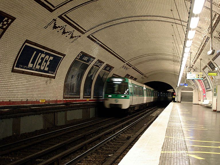 Liège station. Bands of brown tiling run across the ceiling, and station names and poster adverts are framed with brown tiles too. Not also the tiled swag patterns. By Clicsouris (Own work (Photo personnelle)) [CC-BY-SA-3.0], via Wikimedia Commons