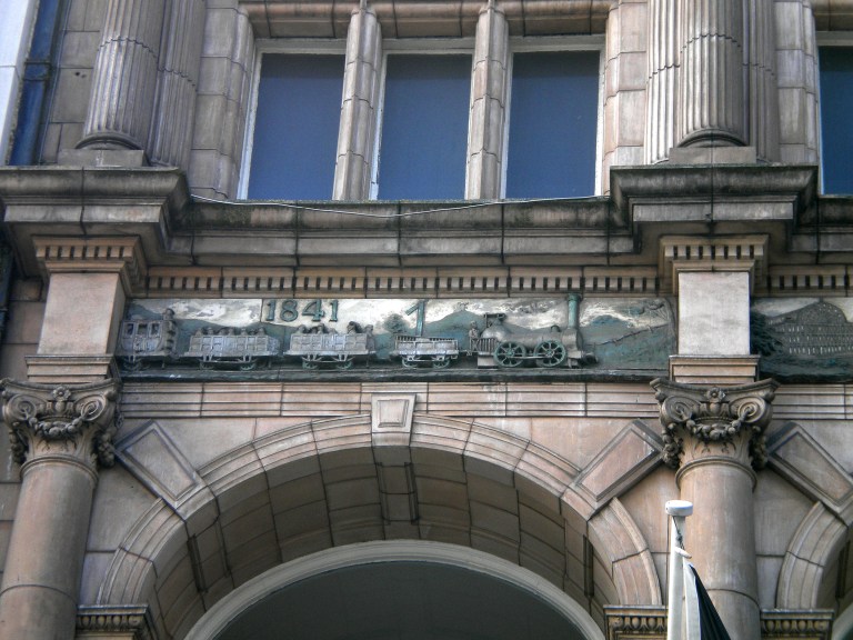 Detail of the frieze on the Thomas Cook Building, Leicester, UK. This shows the 1841 train that invented the charter train business. © Paul Wright (used with permission)
