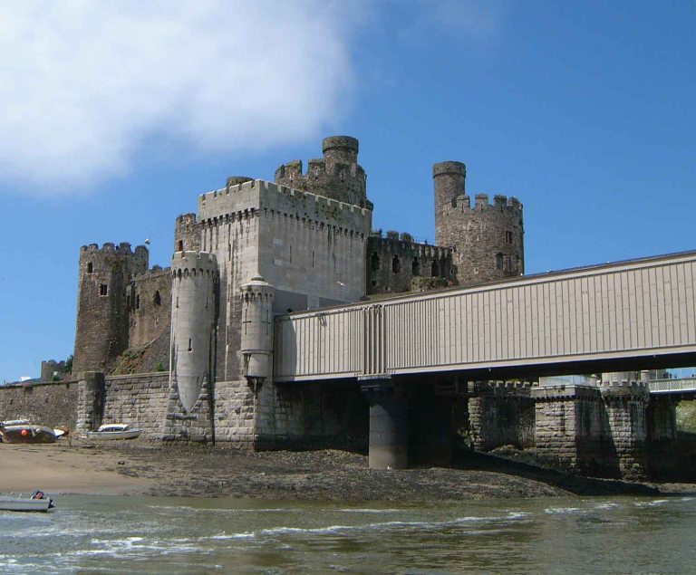 Stephenson's bridge, in front of Conwy Castle. The similarities and differences in design of the details of the two buildings are intriguing. By Mick Knapton at the English language Wikipedia [GFDL or CC-BY-SA-3.0], from Wikimedia Commons