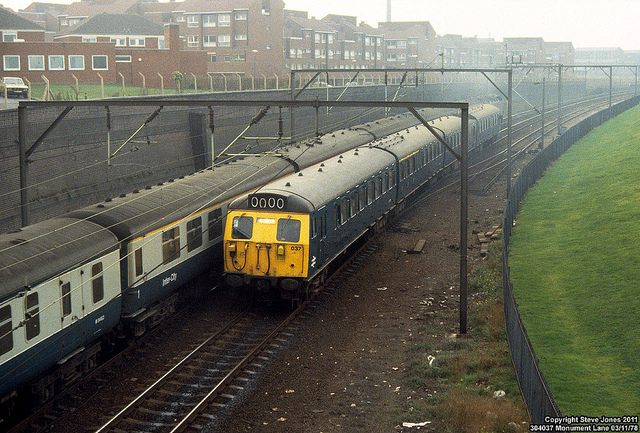 Blue train with blue/grey express train behind. Monument Lane, Birmingham, 1978. Photo by Steve Jones [CC 2.0] via this flickr page