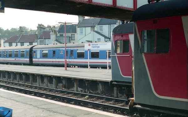 Network SouthEast's visual identity: trains in its red white and blue livery, signage with NSE chevron incorporated in a strip along the lower edge, and lampposts in red. This is Hastings station in 1991. Photo by Daniel Wright [CC BY-NC-ND 2.0] via this flickr page