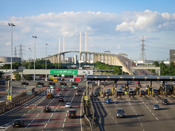 The QEII Bridge at Dartford, east of London. It has extremely long approach ramps to get the roadway high enough to cross the River Thames while still leaving sufficient clearance for ships to pass underneath. This is the problem that a transporter bridge aims to solve. Photo by Nico Hogg [CC BY 2.0] via this flickr page